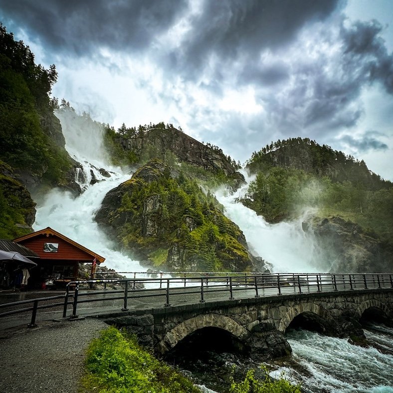 Mächtiger Wasserfall Låtefossen in Norwegen mit Brücke und Straße im Vordergrund
