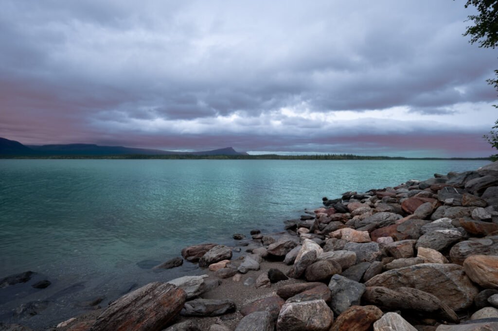 „Dramatische, mystische Seestimmung mit dunklem Himmel und türkisfarbenem Wasser – aufgenommen entlang des Vildmarksvägen in Schweden“