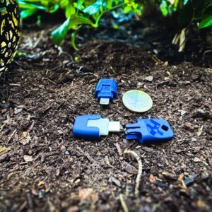 Heat it Insektenstichheiler im Größenvergleich mit 1-Euro-Münze – Lightning & USB-C Variante auf Waldboden