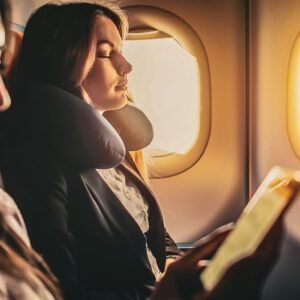 Die besten Reisekissen - Frau mit Nackenkissen im Flugzeug – entspannt schlafen auf Reisen