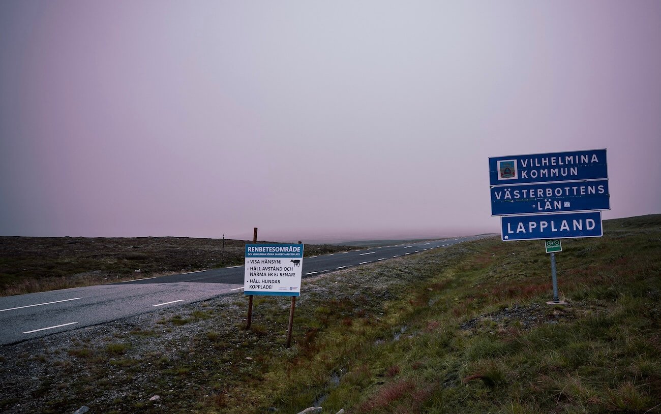 Niemals ohne Thermacell Backpacker -Ortsschild Lappland in Schweden – Nebelstimmung an leerer Straße bei Vilhelmina Kommune, perfekter Einstieg für Camping-Abenteuer.